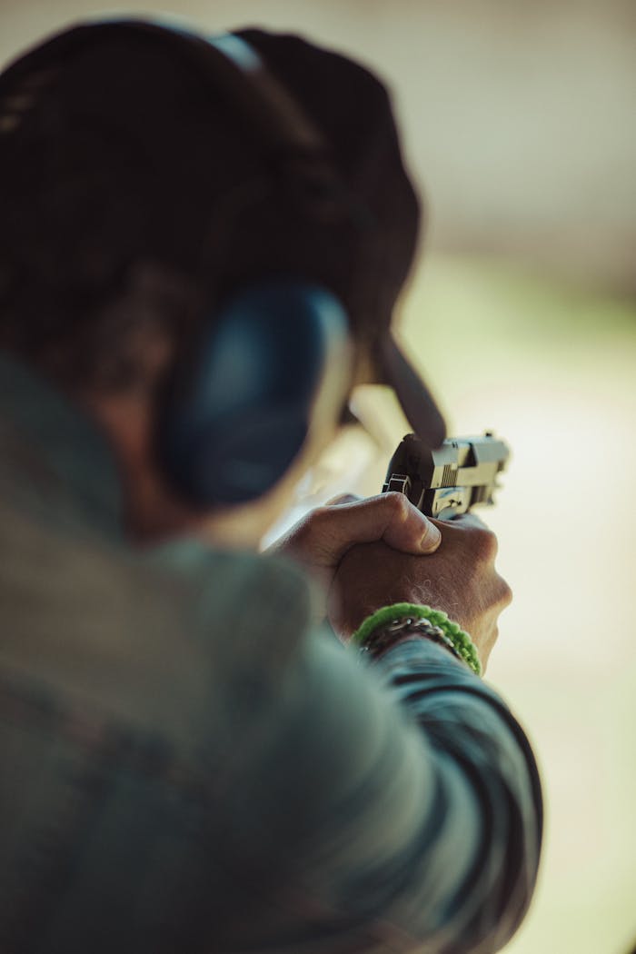 portfolio-04 An individual aiming a pistol at a shooting range wearing ear protection.