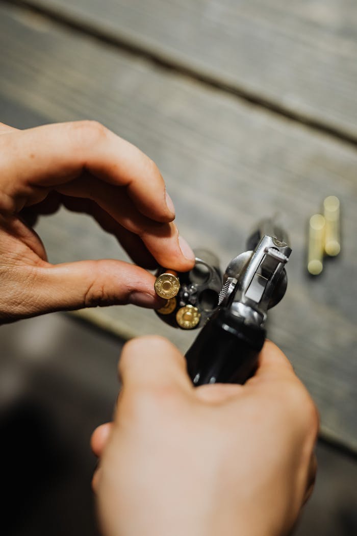 portfolio-02 A detailed shot of hands loading bullets into a revolver on a wooden surface.