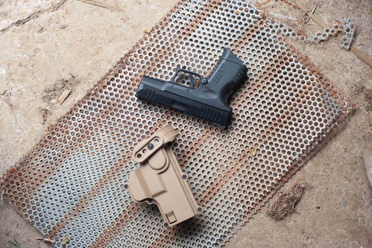 portfolio-03 A handgun and holster on a rusted metal mesh create a rugged outdoor scene.